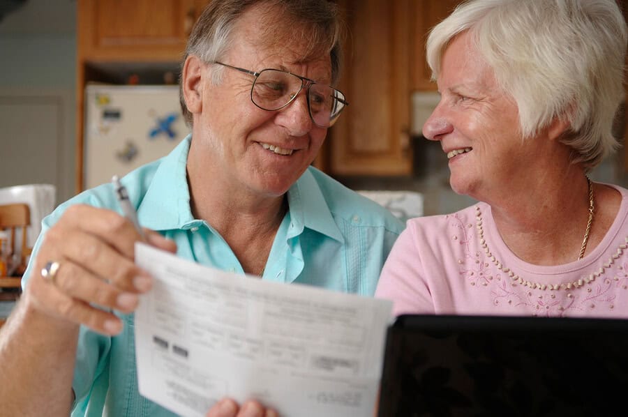 Senior couple smiling while looking at documents.